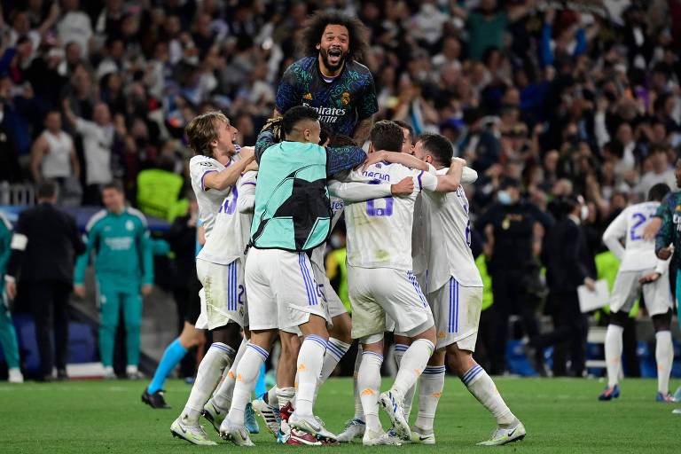 Com o uniforme de reserva, o lateral Marcelo salta sobre companheiros de Real Madrid ao celebrar a classificação para a final da Champions League, depois do triunfo diante do Manchester City