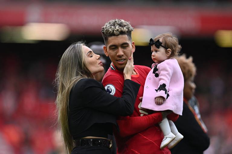 Roberto Firmino segura a fiha pequena enquanto ganha um beijo da esposa depois do jogo em que o Liverpool ganhou, no estádio de Anfield, do Wolverhampton e ficou com a segunda colocação no Campeonato Inglês