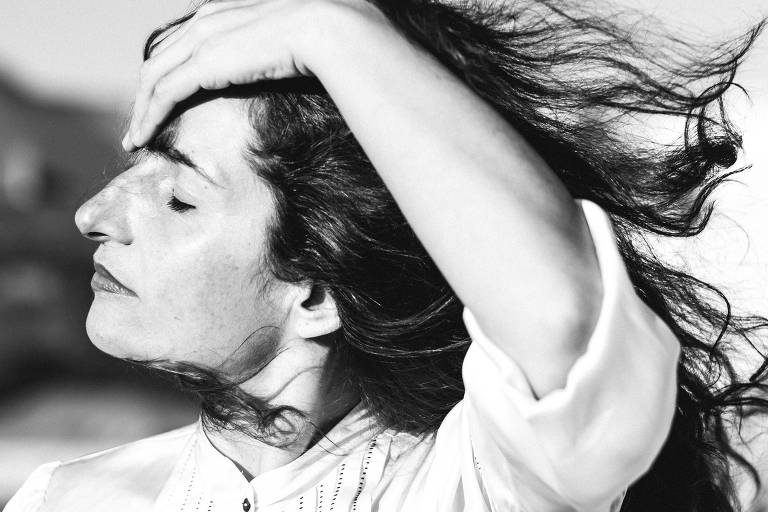 Joana Bértholo arruma o cabelo contra o vento, em preto e branco