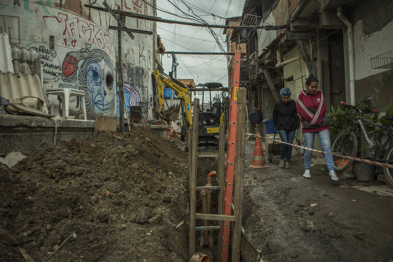 Moradoras observam obras de saneamento na favela do Moinho, em São Paulo

