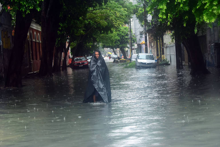 Homem caminha por rua alagada no Recife 