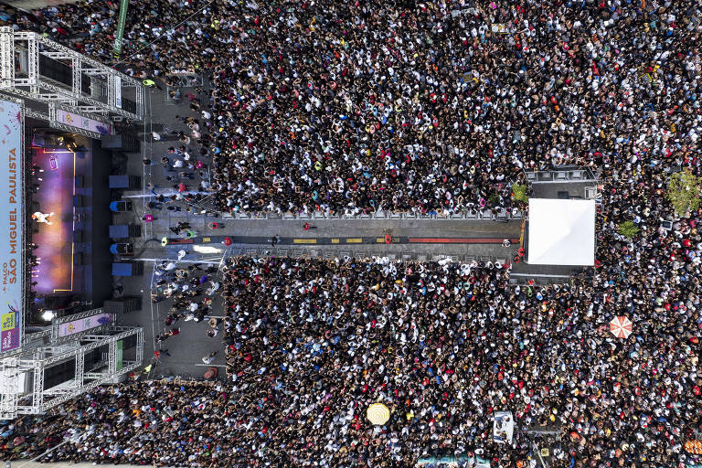 Imagem aérea mostra a estrutura do palco e o artista em meio a multidão durante show do Barões da Pisadinha