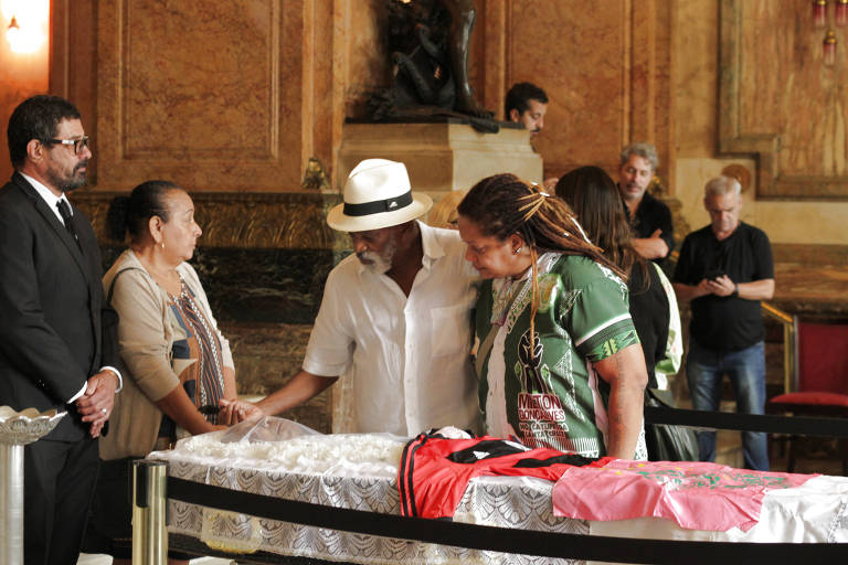 Imagem mostra o caixão do ator Milton Gonçalves e familiares se despedindo, no velório