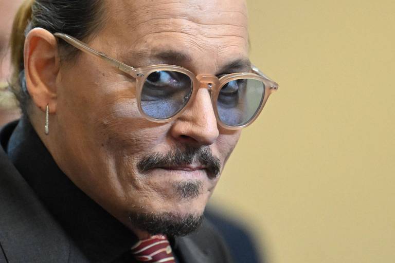 Johnny Depp sorri de canto de boca durante o julgamento em Fairfax, na Virginia

