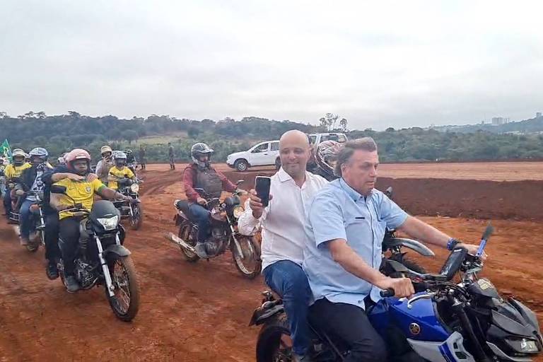 O presidente Jair Bolsonaro (PL) pilota moto em estrada de terra com o deputado federal Major Vitor Hugo (PL-GO) na garupa durante visita a Jataí (GO)