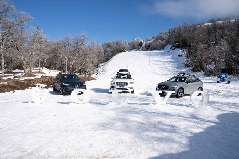 Três carros estacionados sobre a neve, atrás de letreiro branco escrito Volvo