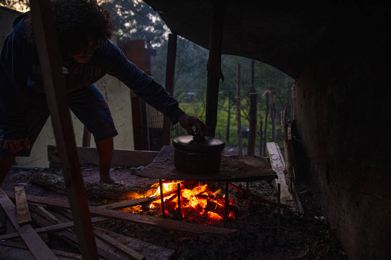 Morador da ocupação Jorge Hereda, que atende a 300 famílias, acende fogueira paga cozinhar feijão