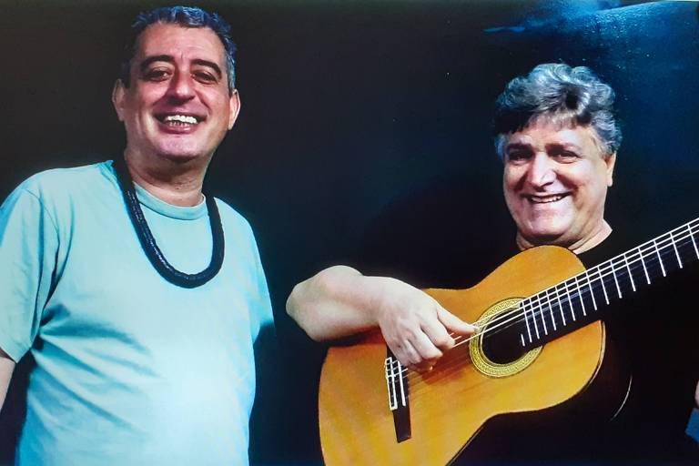 Em foto colorida, o  cantor Didu Nogueira e o violonista Jorge Simas posam para a câmera