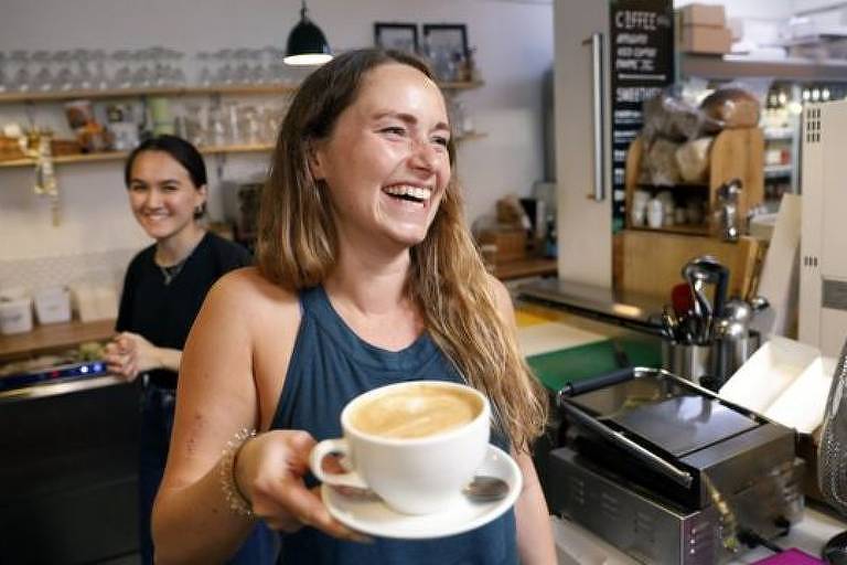 Imagem de uma mulher com uma xícara na mão sorrindo
