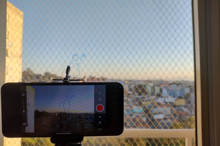 Celular filma janela com tela de proteção em filme feito pela professora Michele Gesteira, da rede estadual