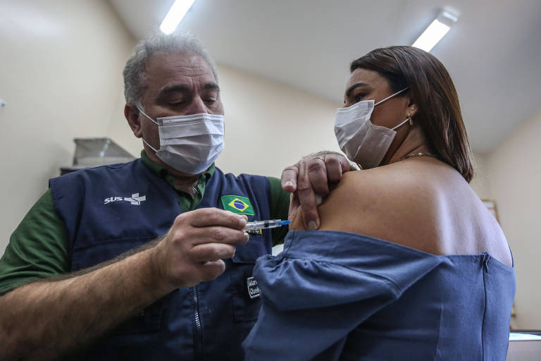 De colete do SUS, Marcelo Queiroga aplica vacina em mulher de máscara