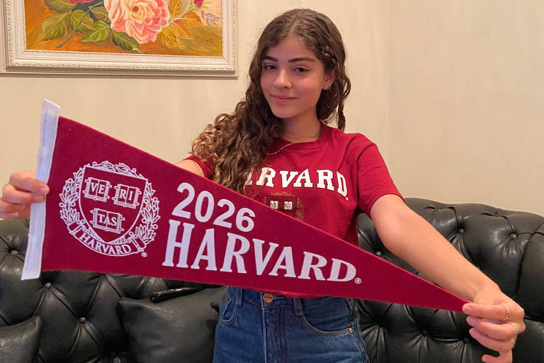 Sofia Santos segura uma bandeira vermelha, onde se lê: "2026 Harvard"