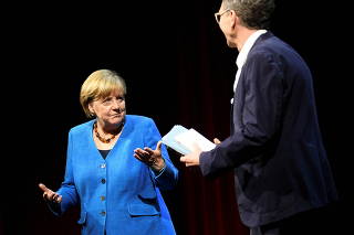 Former German Chancellor Angela Merkel talks with author Alexander Osang, in Berlin