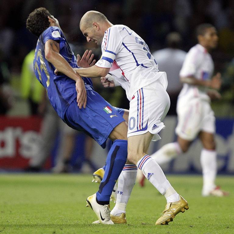 O francês Zidane, que é careca e usa uniforme branco, desfere cabeçada no peito italiano Materazzi, que usa uniforme azul, na final da Copa do Mundo de 2006, na Alemanha