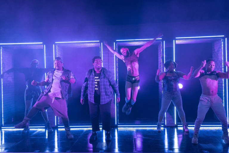 cinco atores pulando no palco