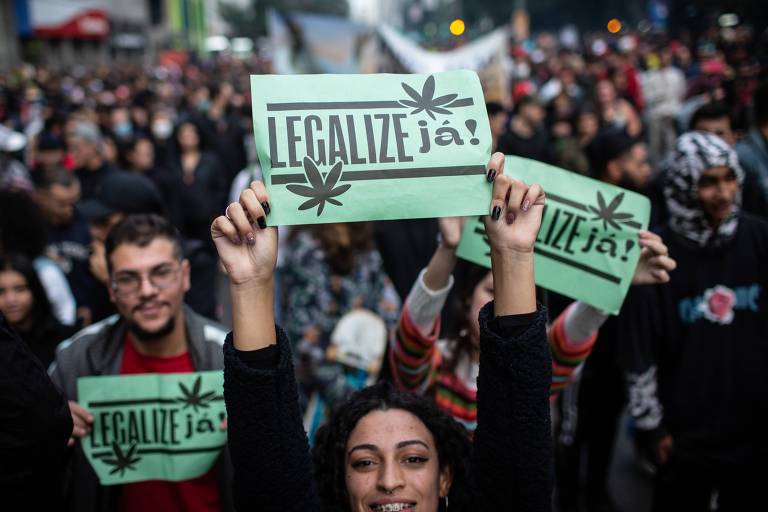 Jovem segura cartaz escrito 'legalize já'  em meio a manifestantes durante marcha da maconha em São Paulo 