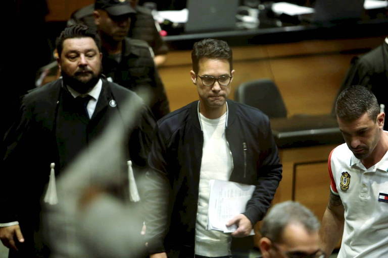 homem de óculos e camisa branca ao lado de advogado de roupas de tribunal na sala de audiencia do TJ do Rio