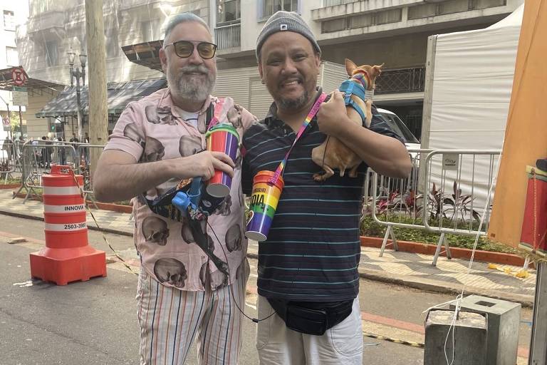 Dois homens posam para a foto com copos coloridos comprados na feira