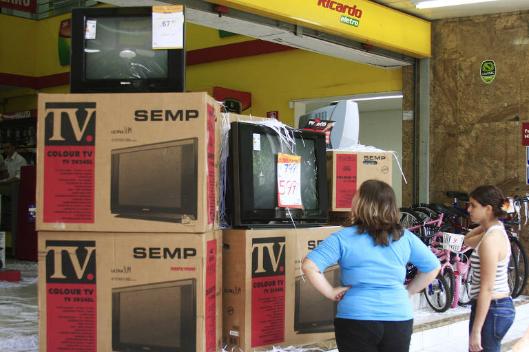 mulher com criança em frente a uma loja com TVs à venda