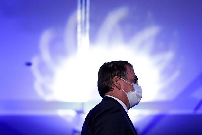 Bolsonaro de máscara em frente a fundo azul quase roxo com mancha de luz branca