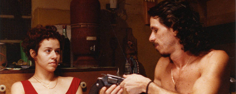 No papel de Vitor, ator Paulo Vespúcio está sem camisa e segura um revólver calibre 38 pelo cano. Na pele da cabeleireira Dalva, a atriz Leona Cavalli, de vestido vermelho e mãos juntas, olha para o rosto de Vespúcio. Ambos estão sentados em volta de uma mesa