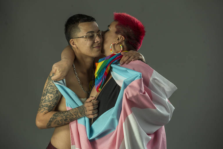 Glaucia Salles, 29, bissexual, e o filho Thaylor Henrique, 15, o MC TH, trans; ela com a bandeira arco-íris, com abraço com a bandeira trans
