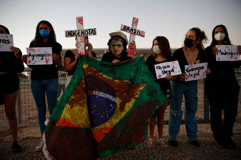 Manifestantes carregam cruzes, uma bandeira brasileira manchada e uma máscara do presidente Jair Bolsonaro