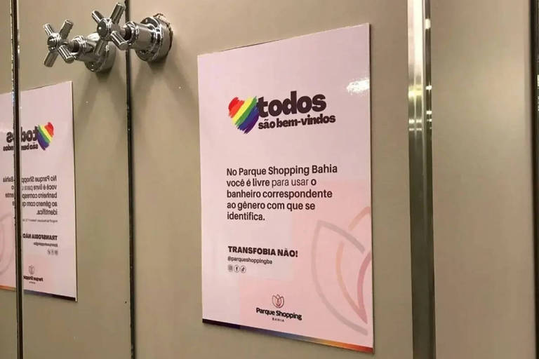 cartaz branco com coração com cores do arco-íris e dizeres sobre a transfobia em banheiros
