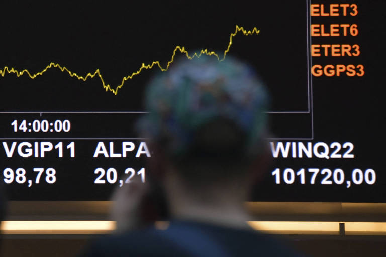 Homem observa painel com gráfico de ações na sede da Bolsa de Valores, em São Paulo