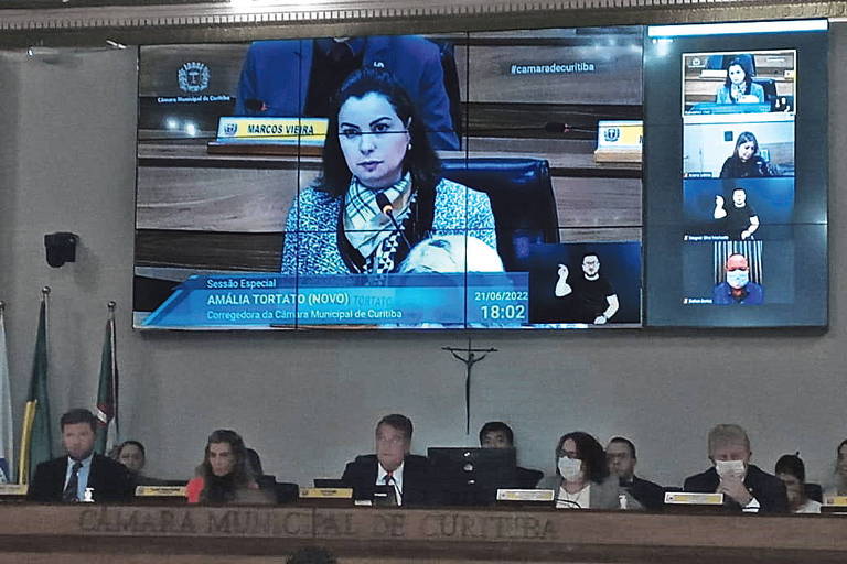 imagem de mulher projetada em tela da camara de curitiba; embaixo, mesa diretora dos vereadores