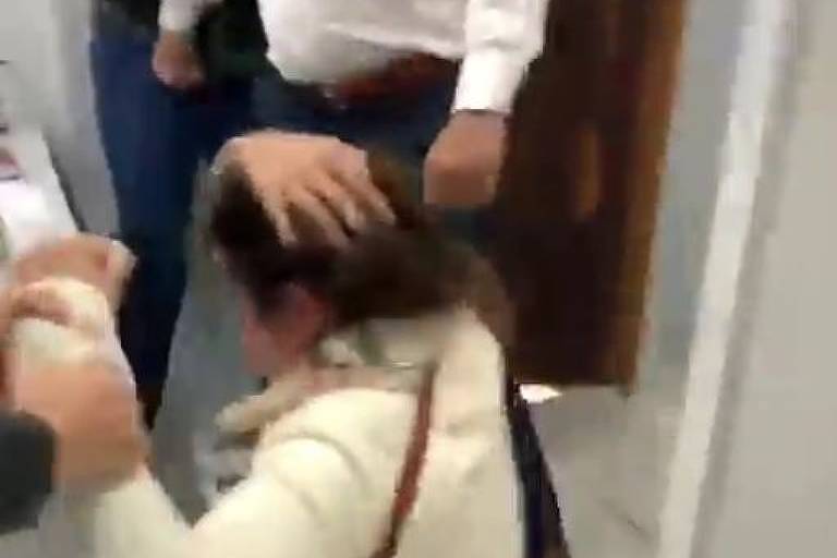 imagem de mulher no chão após ser agredida por homem em pé