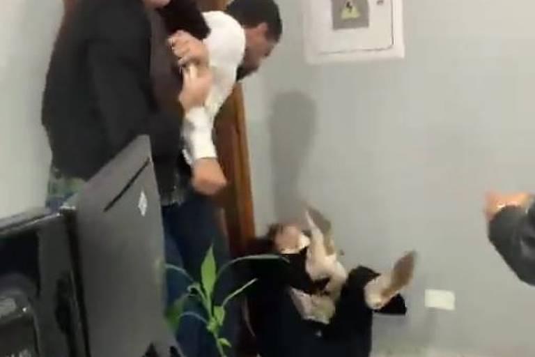 frame de video em que mulher está no chão e homem a agride e outra mulher faz expressão de medo