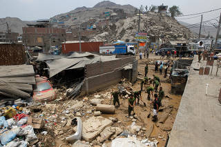 Peruvian soldiers help remove mud from affected houses after a landslide in San Juan de Lurigancho distritct in Lima