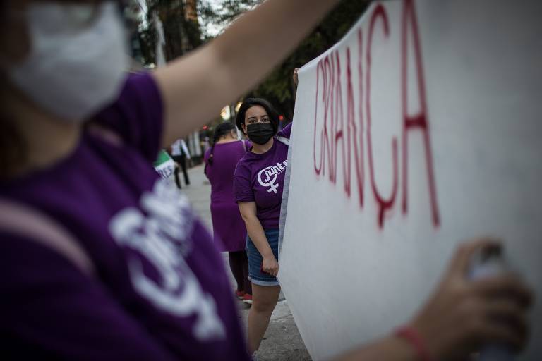 Manifestantes escrevem a palavra "criança" em cartaz