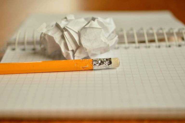 Caderno, lápis e papel amassado