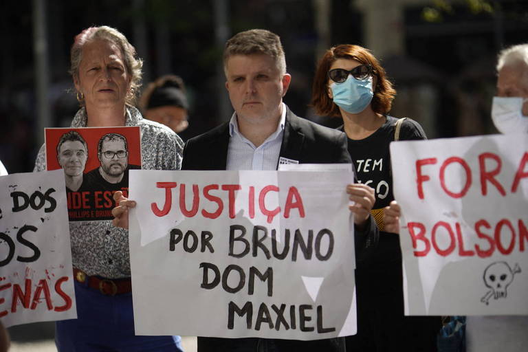 Pessoas com cartazes em protesto. Um deles diz: Justiça para Bruno, Dom e Maxiel