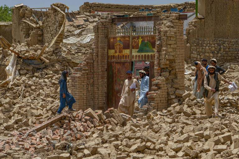 Sobreviventes de terremoto caminham por casas destruídas para avaliar os danos no distrito de Bermal, na província de Paktika