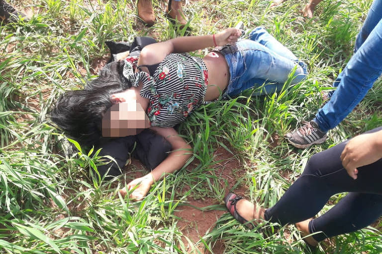 Imagem mostra uma mulher ferida por arma de fogo deitada em um chão de terra.
