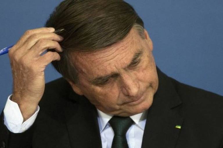 Bolsonaro coça cabeça com caneta