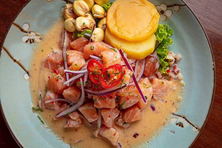 A foto mostra um prato azul claro com cubos de salmão e rodelas de batata doce