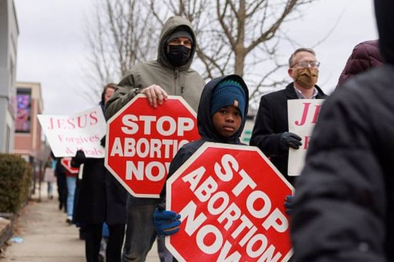 Manifestantes seguram placas escrito: stop abortion now