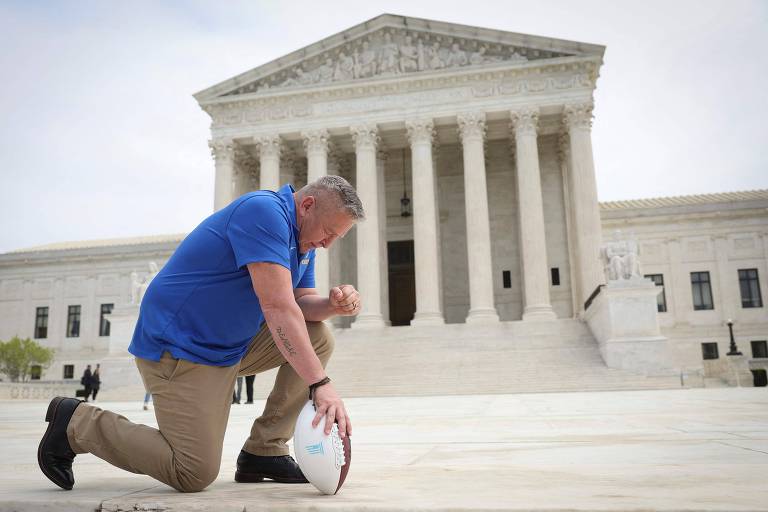 O treinador escolar Joseph Kennedy se ajoelha em frente à Suprema Corte dos EUA
