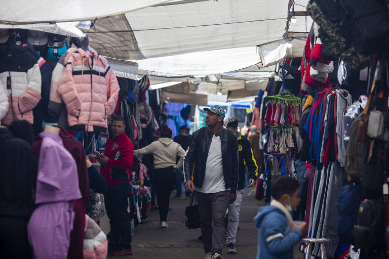 Corredor de camelôs no centro de São Paulo, mostra variedade de produtos e movimentação de pedestres 