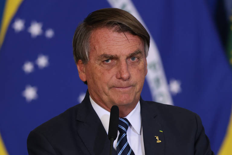 Bolsonaro é um homem branco, idoso, que está na frente de uma bandeira verde e amarela