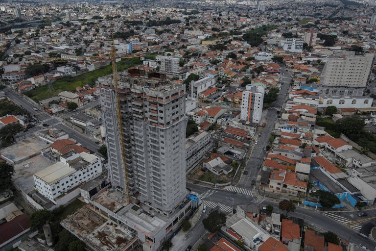 Imagem aérea mostra prédio sendo construído em meio a um bairro cheio de residências e outros prédios menores