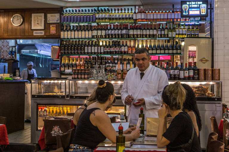 Garçom anota pedidos de clientes em restaurante no centro do Rio de Janeiro
