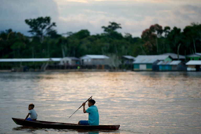 Pai e filho andam de barco a remo no rio Amazonas