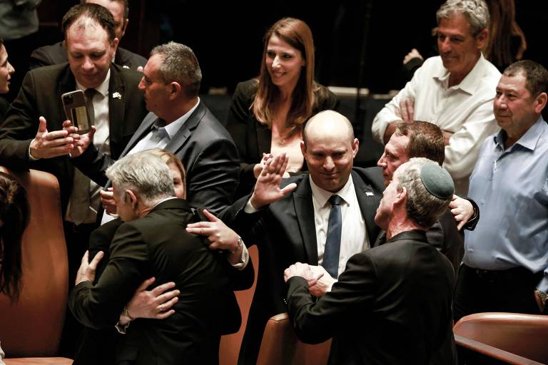 O primeiro-ministro Naftali Bennett (centro) cumprimenta colegas após dissolução do Parlamento de Israel; à esquerda, de costas, Yair Lapid, que assumirá o governo de forma provisória, abraça deputada