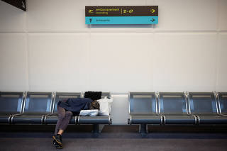 A passenger sleeps on a bench at the Nantes-Atlantique airport in Bouguenais
