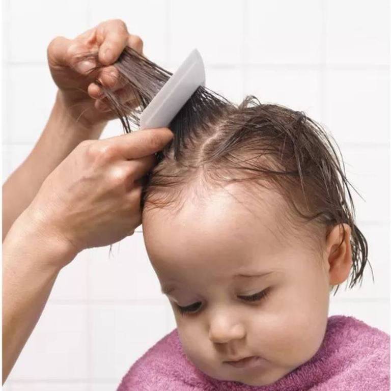 Mãe penteia os cabelos de uma menina de cerca de dois anos